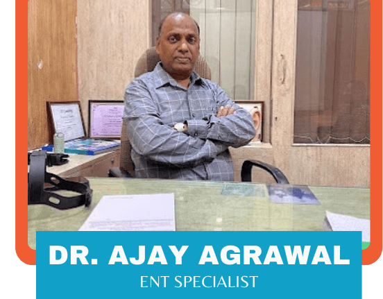 Dr. Ajay Agrawal, an ENT specialist, sitting at his desk in his office with his arms crossed.