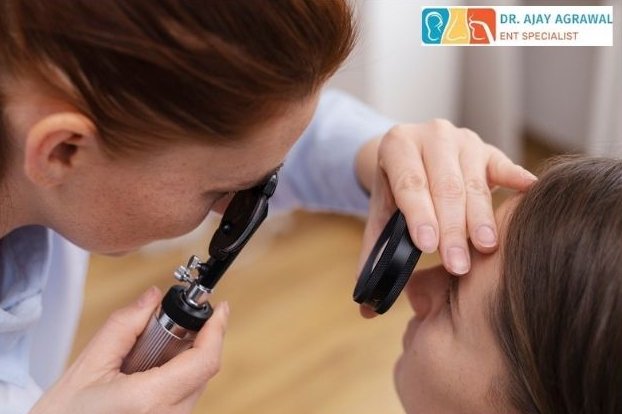 A medical professional uses an ophthalmoscope to examine a patient's eye. The logo and name of Dr. Ajay Agrawal, ENT Specialist, are in the corner.