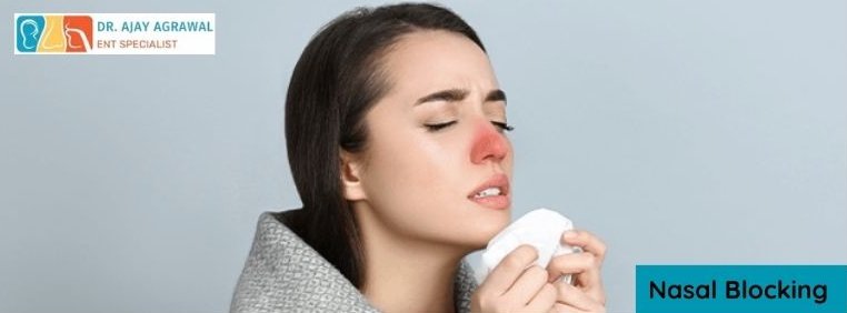 A woman holds a tissue to her red-highlighted nose, looking uncomfortable. A blue box contains the text "Nasal Blocking". The logo and name of Dr. Ajay Agrawal, ENT Specialist, are also included.